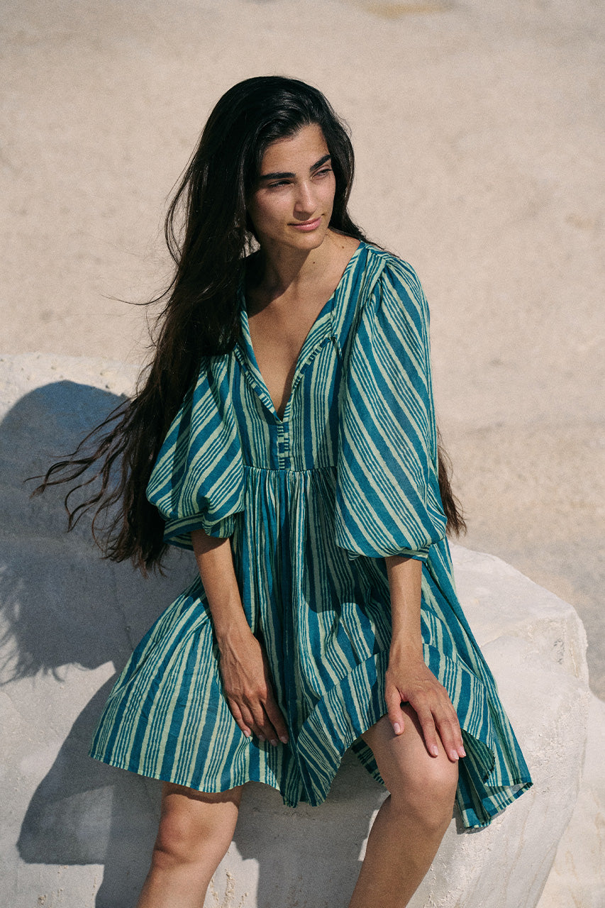 Woman wearing a green and blue striped dress on a sandy background