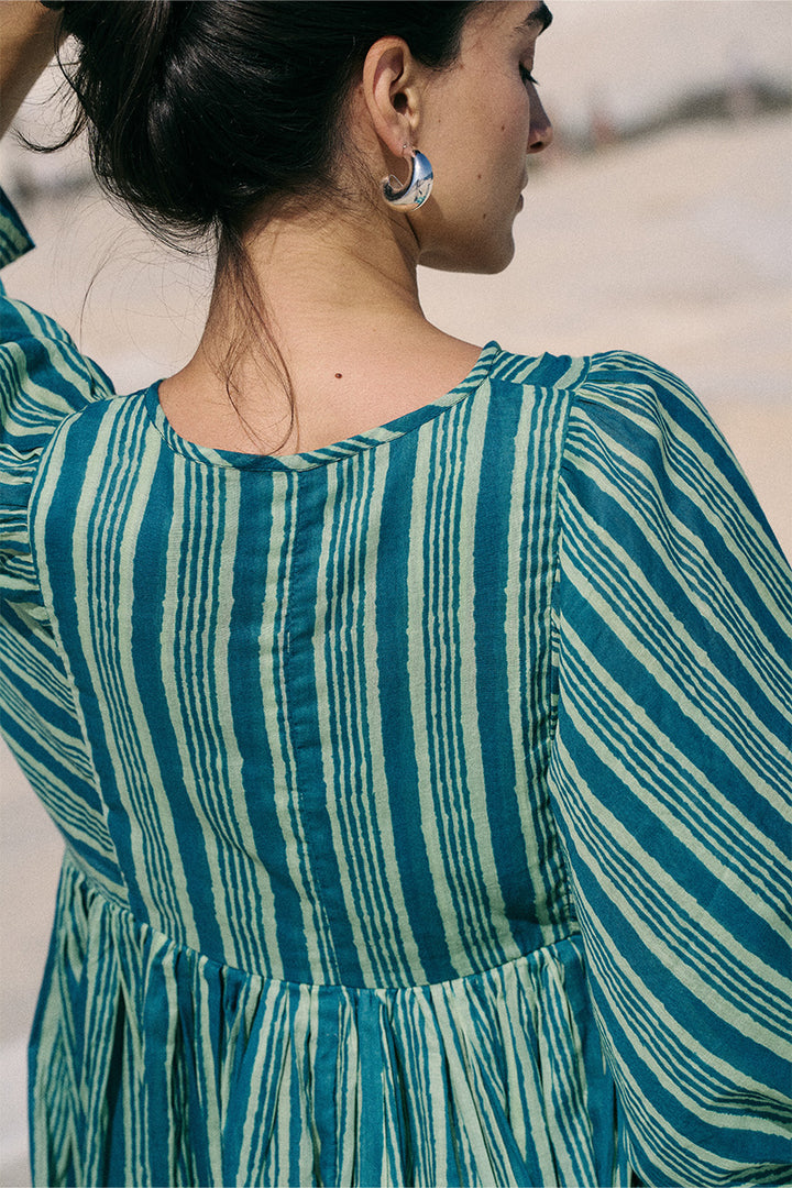 Woman wearing a blue and green striped dress with a blurred background